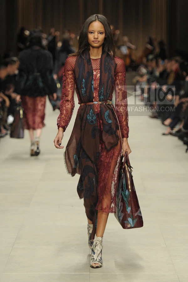 Model walking in a burgundy lace midi dress with a printed scarf, thin belt, and floral-print open-toe ankle boots.