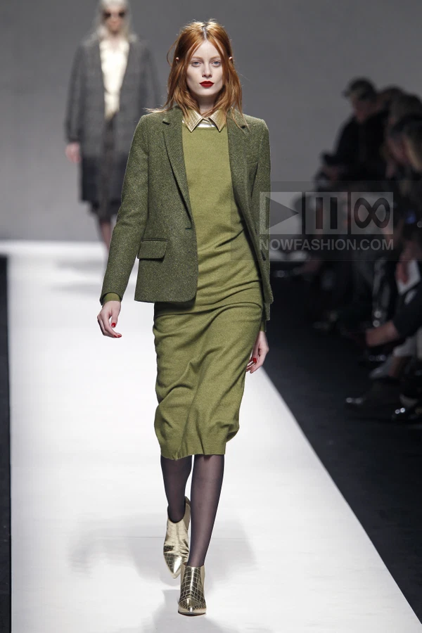 Model walking in a green wool blazer and matching midi knit dress with gold metallic ankle boots on a runway.
