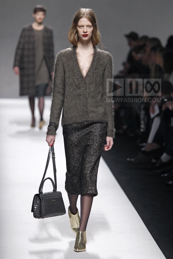 Model walking in a fuzzy dark gray v-neck cardigan, a dark herringbone pencil skirt, and metallic gold ankle boots.