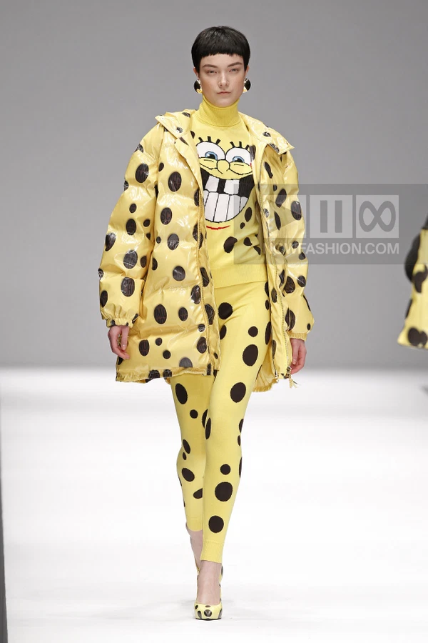 Model wearing a yellow puffer jacket with black polka dots over a matching yellow knit sweater and leggings.