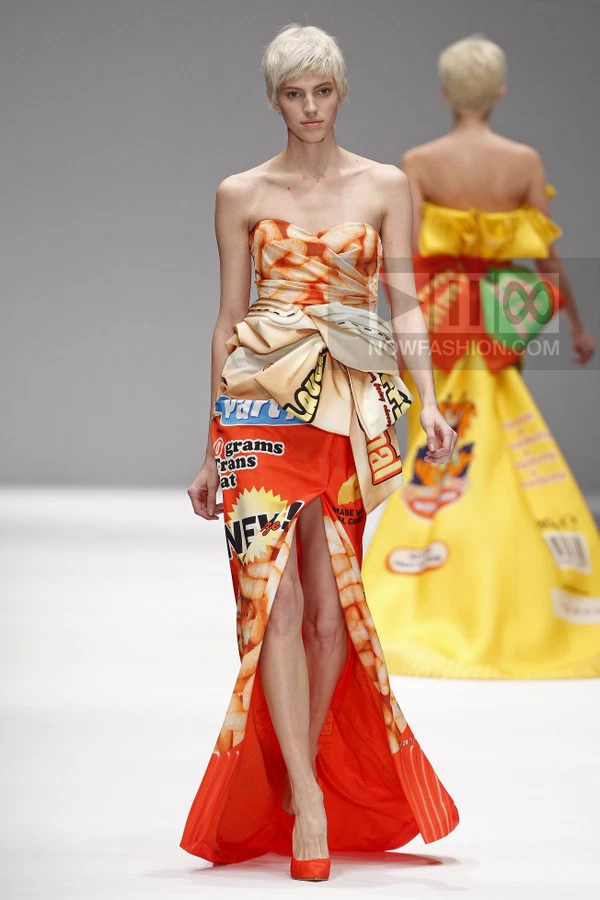 Model wearing a strapless floor-length gown with a snack-food-inspired graphic print and a high front slit.