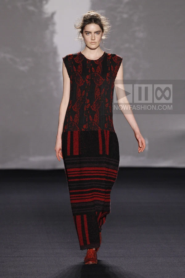 A model walks the runway in a sleeveless midi dress with a black and red floral bodice and a striped knit skirt.