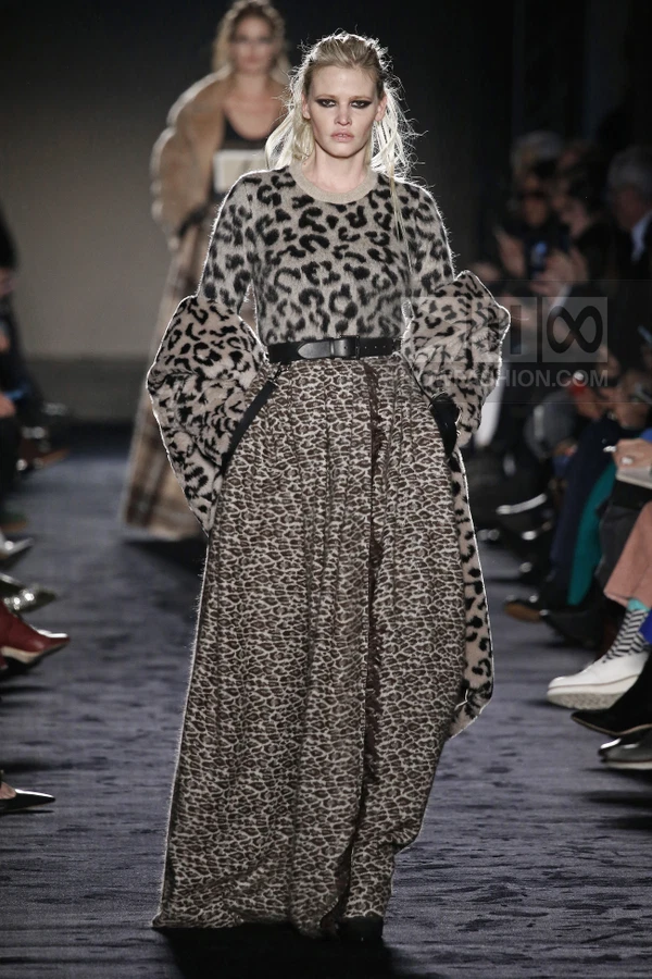 Model on runway wearing a leopard print sweater, matching long skirt, and a leopard print coat draped over shoulders.