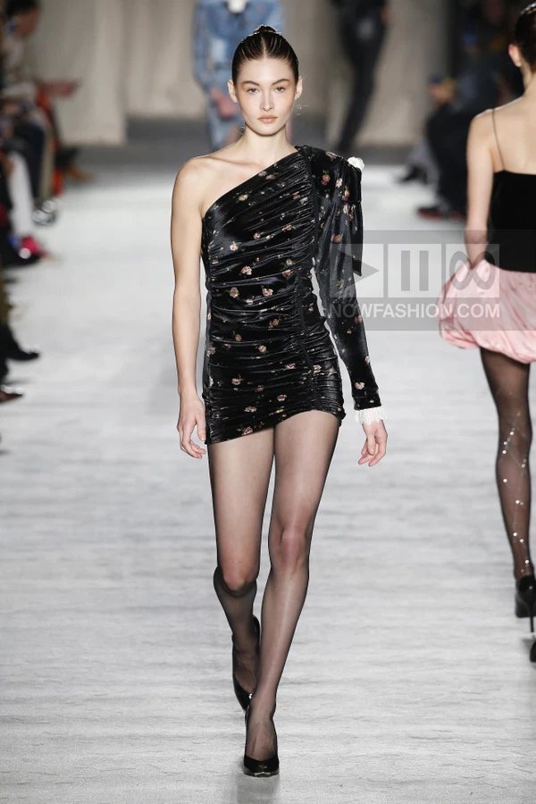 A model walks the runway in a black velvet one-shoulder mini dress with floral print and ruched detailing.