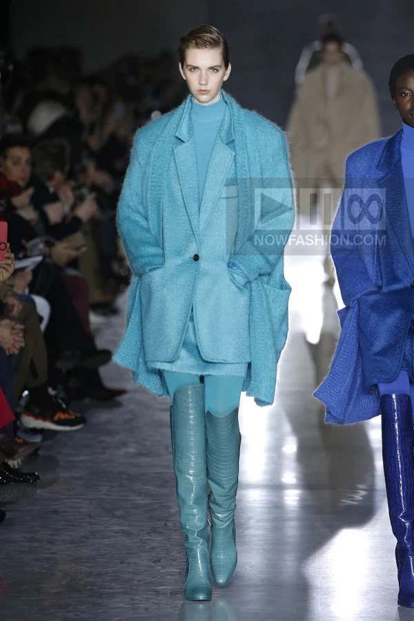 Model wearing a turquoise mohair coat over a matching turtleneck and skirt with knee-high crocodile-embossed boots.