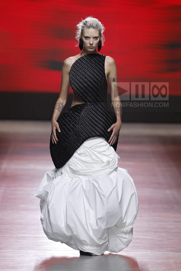 Model on runway wearing a black woven structured bodice over a voluminous white gathered skirt.